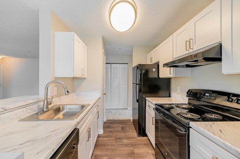 A kitchen with white cabinets and a black refrigerator.